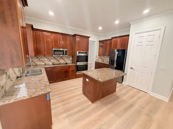 a large kitchen with stainless steel appliances granite countertop a refrigerator a sink and a stove