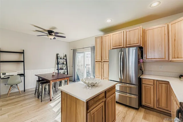 a kitchen with stainless steel appliances kitchen island granite countertop a refrigerator a sink dishwasher and a stove with wooden floor