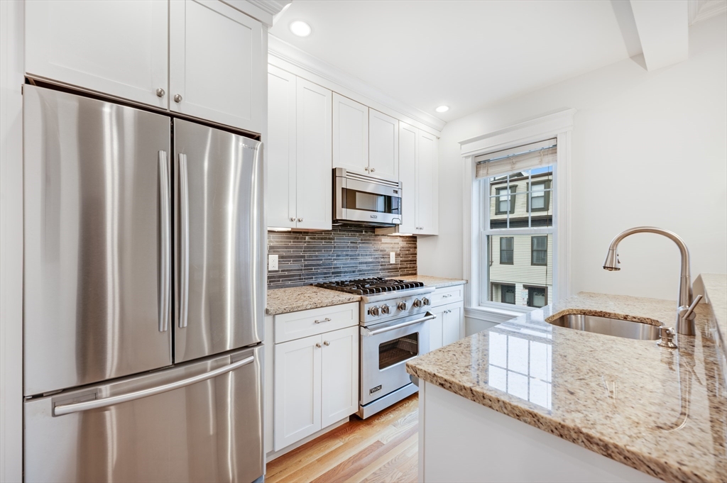 a kitchen with granite countertop a refrigerator stove and sink