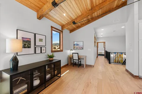 a view of a hallway with furniture and wooden floor