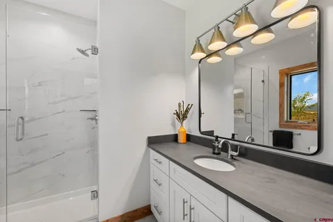 a bathroom with a granite countertop sink a mirror and a shower