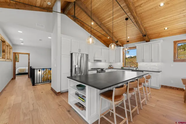 a kitchen with stainless steel appliances granite countertop a kitchen island a stove a refrigerator a oven a sink with island and chairs