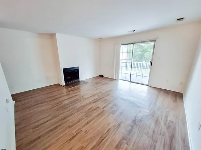 a view of empty room with wooden floor and fireplace