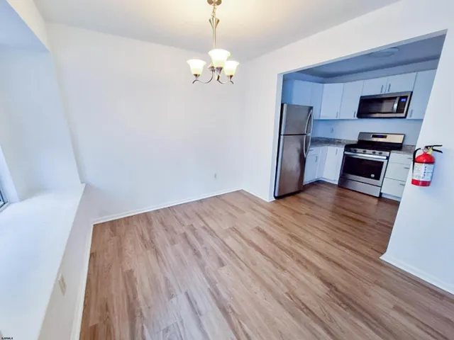 a room with wooden floor and stainless steel appliances