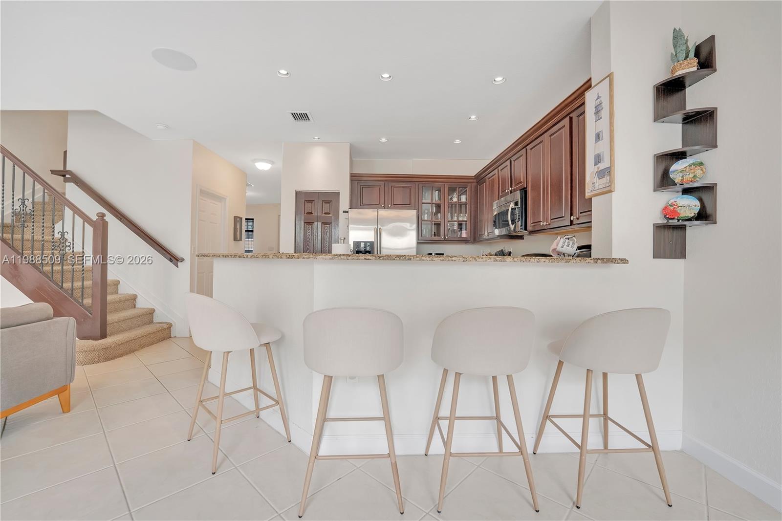 23484 Southwest 112th Court Homestead, FL 33032 - Photo 6 of 33 a kitchen with stainless steel appliances kitchen island granite countertop a dining table chairs and a refrigerator