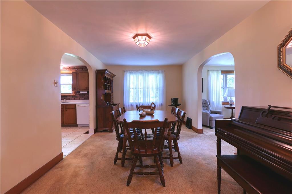 The dining room features wide arched doorways and hardwood floor beneath the carpet.