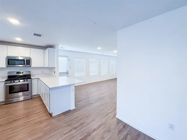 a large kitchen with wooden floors and stainless steel appliances