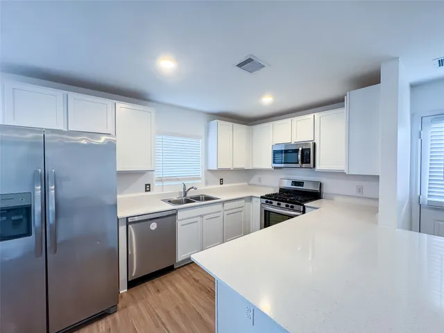 a kitchen with stainless steel appliances a sink stove refrigerator and cabinets
