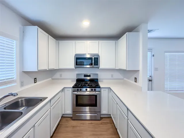 a kitchen with a sink stove top oven and cabinets