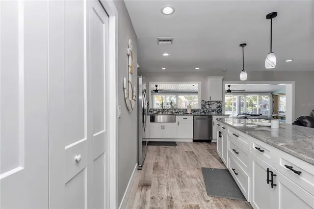 a kitchen with white cabinets and wooden floor