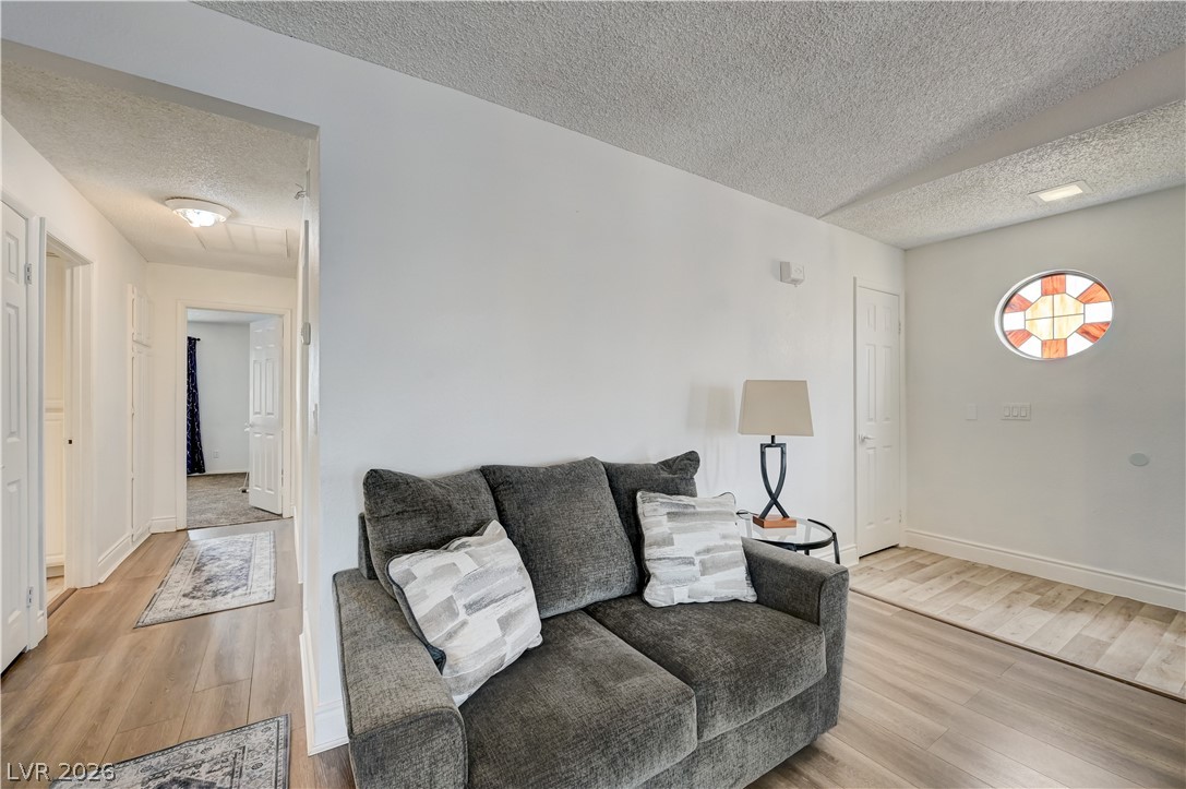 1751 East Reno Avenue, Unit 228 Las Vegas, NV 89119 - Photo 8 of 39 Welcoming living space showcases durable plank flooring, smooth white walls, and a distinctive circular stained-glass window.