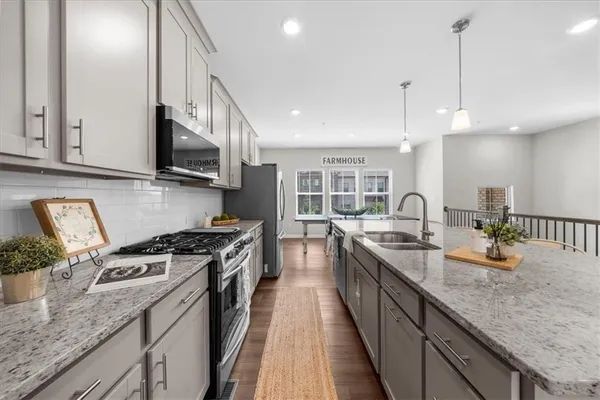a kitchen with stainless steel appliances granite countertop a sink a stove and a wooden cabinets