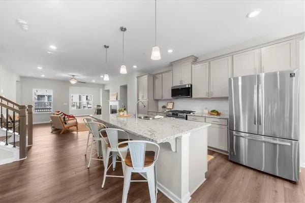a kitchen with stainless steel appliances granite countertop a refrigerator a stove a sink a dining table and chairs with wooden floor