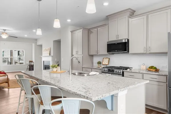 a kitchen with stainless steel appliances granite countertop a sink a stove a microwave a center island and chairs