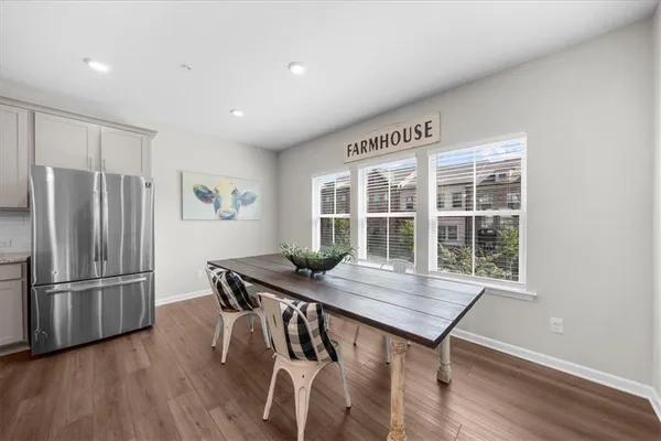 a kitchen with stainless steel appliances granite countertop a table chairs and a refrigerator