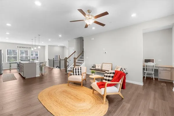 a living room with furniture kitchen view and a wooden floor