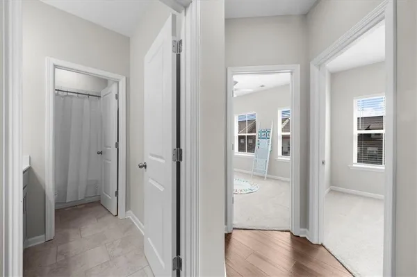 a view of a hallway with wooden floor and a bathroom