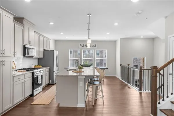 a view of a kitchen with kitchen island stainless steel appliances wooden floor dining table and wooden floor