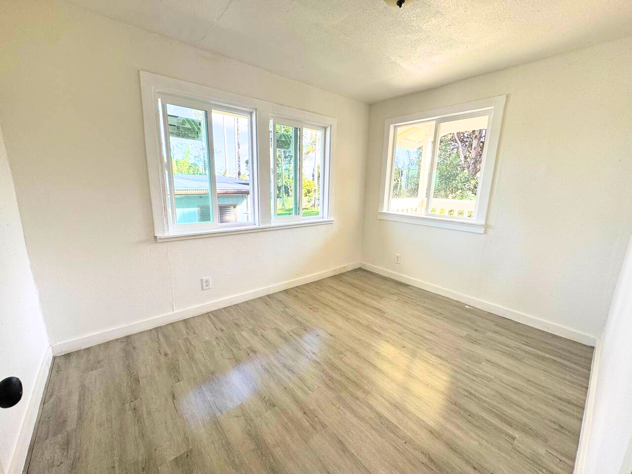 18-4069 Mauna Kea Drive Mountain View, HI 96771 - Photo 7 of 12 an empty room with wooden floor and windows