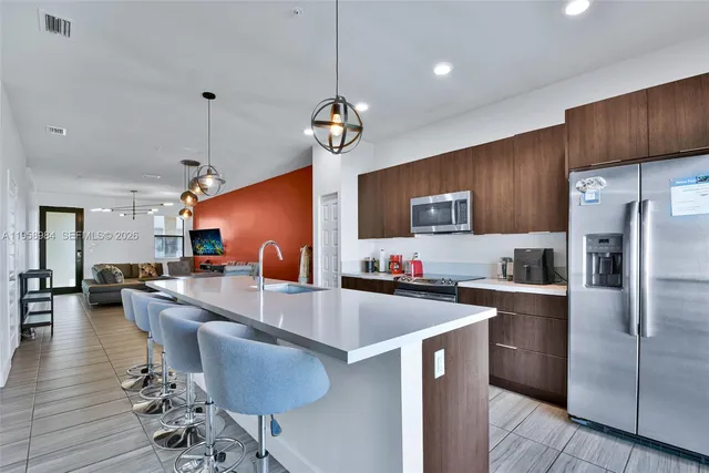 a kitchen with a refrigerator a stove top oven a sink dishwasher a dining table and chairs with wooden floor