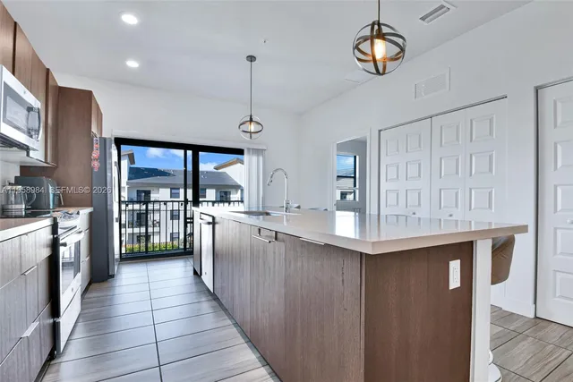 a kitchen with stainless steel appliances granite countertop a stove kitchen island a refrigerator and a stove top oven