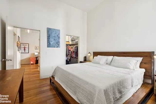 a spacious bedroom with a bed and wooden floor