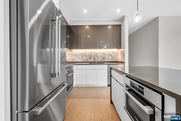 a kitchen with granite countertop a refrigerator and white cabinets