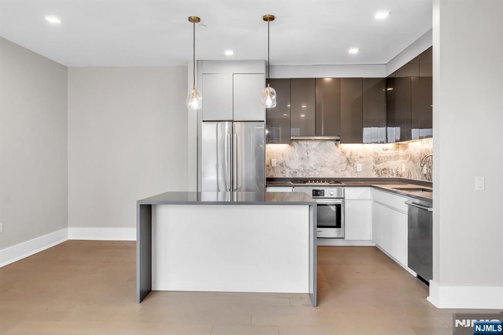 7101 River Road, Unit 202B North Bergen, NJ 07047 - Photo 8 of 17 a kitchen with kitchen island a counter top space a sink and stainless steel appliances