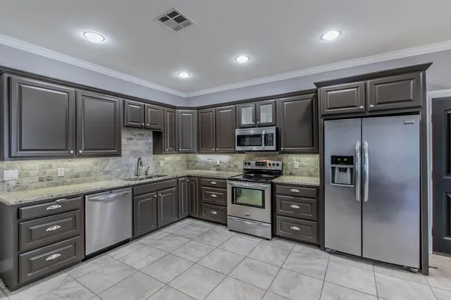 a kitchen with stainless steel appliances granite countertop a refrigerator and a stove top oven