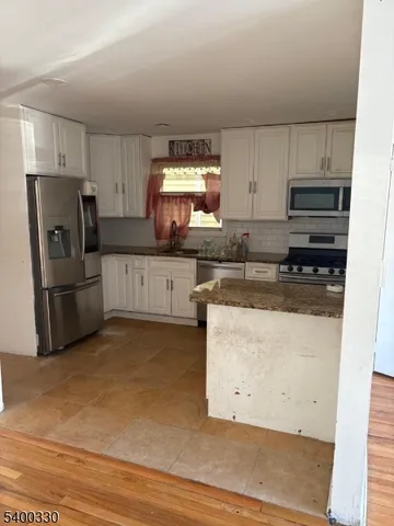 a kitchen with granite countertop a refrigerator and a stove top oven