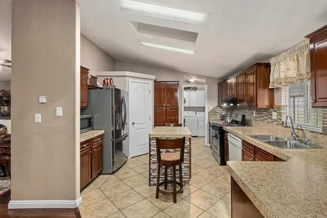 a kitchen with stainless steel appliances kitchen island granite countertop a refrigerator and a stove