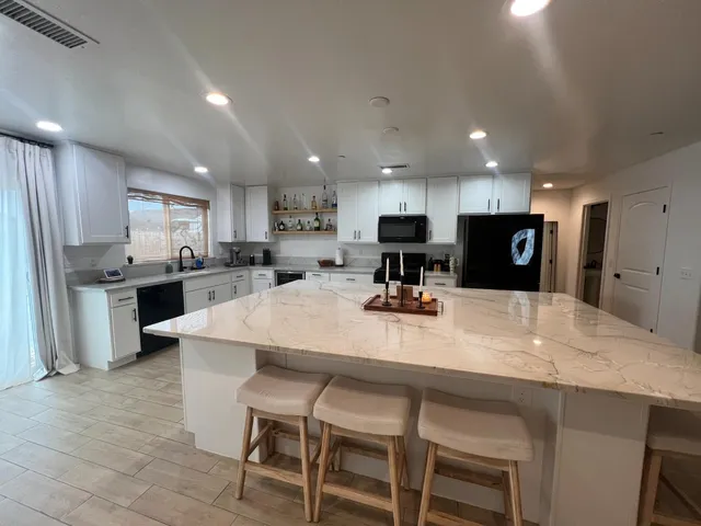 a kitchen with stainless steel appliances kitchen island granite countertop a table chairs sink and cabinets