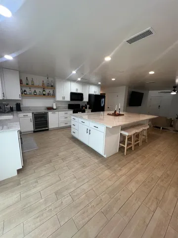 a large white kitchen with stainless steel appliances kitchen island granite countertop a large counter top a stove a sink and a refrigerator