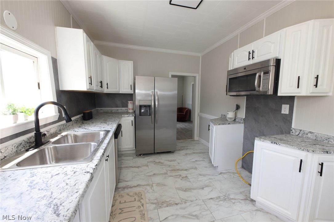 416 5th Street Chester, WV 26034 - Photo 5 of 24 Kitchen featuring white cabinetry, light-toned countertops, a stainless steel double-basin sink with a matte black faucet, and stainless steel appliances