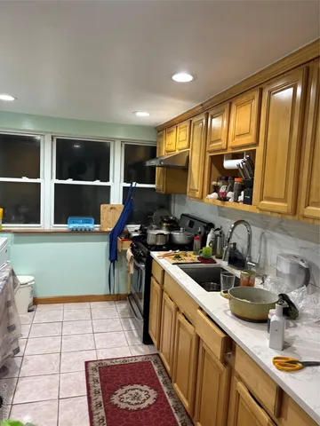 a kitchen with a sink and a stove top oven a wooden floor