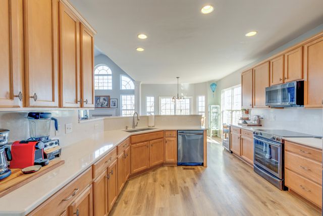 a large kitchen with stainless steel appliances granite countertop a lot of counter space and wooden floors