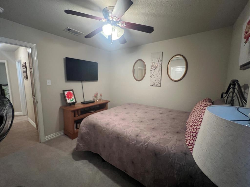 312 McAfee Street Mabank, TX 75147 - Photo 38 of 40 a bedroom with a bed and a flat tv screen on the dresser