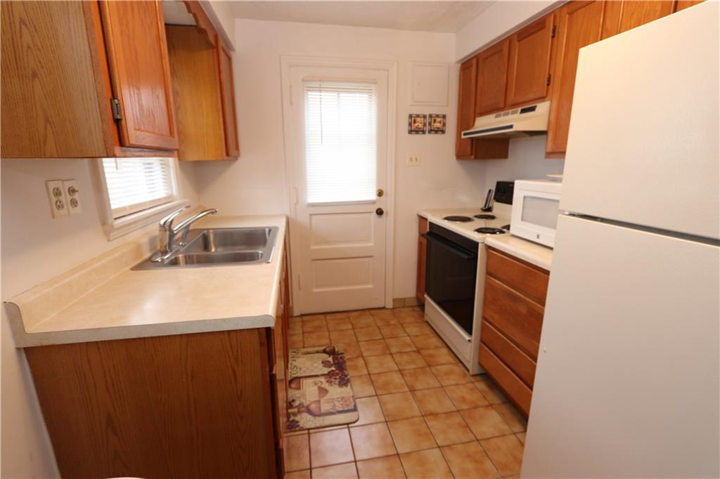 511 Bower Hill Road Pittsburgh, PA 15228 - Photo 7 of 25 Kitchen with Oak Cabinetry, Tile Flooring, Neutral Countertops, Double Stainless Sink, Electric Stove, Refrigerator and Microwave.