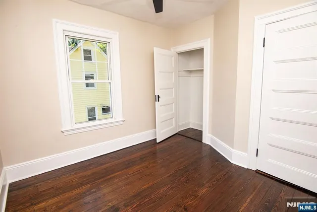 an empty room with wooden floor closet and windows