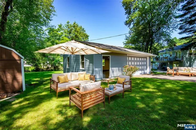 a backyard of a house with table and chairs under an umbrella