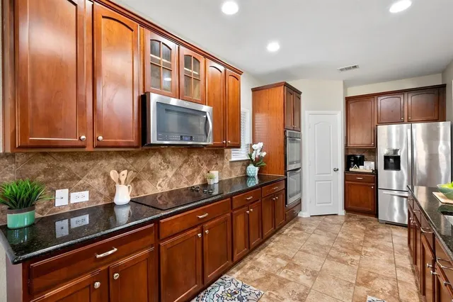 a kitchen with stainless steel appliances granite countertop a refrigerator and a stove top oven