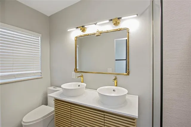 a bathroom with a granite countertop sink mirror vanity and toilet
