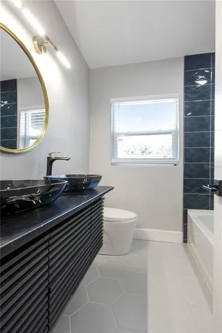 a spacious bathroom with a granite countertop toilet a sink and a mirror
