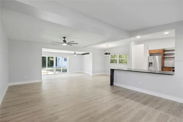 a view of an empty room with window and wooden floor