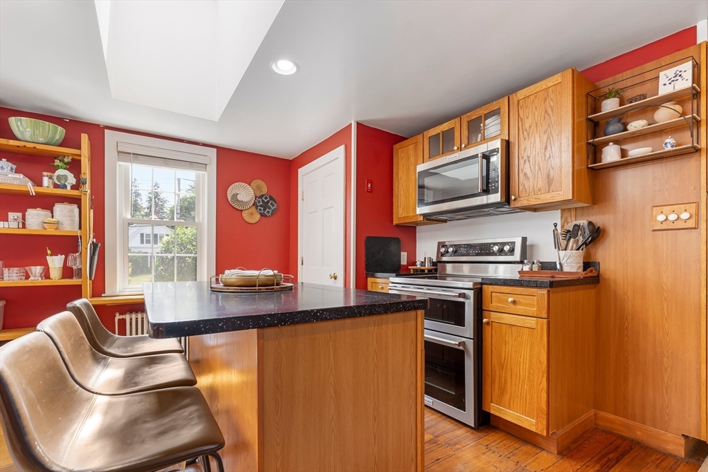 172 Union Street Weymouth, MA 02190 - Photo 13 of 40 a kitchen with stainless steel appliances granite countertop a stove top oven a sink dishwasher a dining table and chairs with wooden floor