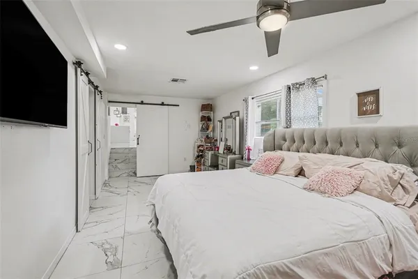 a spacious bedroom with a bed and a flat screen tv