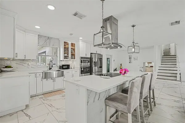 a kitchen with stainless steel appliances kitchen island granite countertop a table chairs and white cabinets