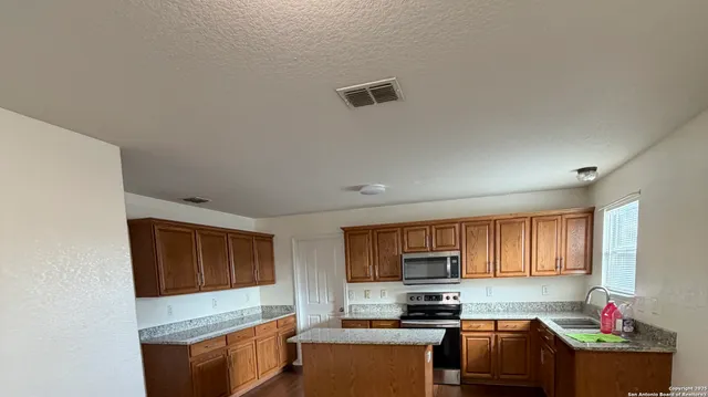 a kitchen with granite countertop a stove top oven microwave and cabinets