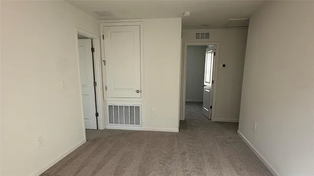 a view of an empty room with closet and a window