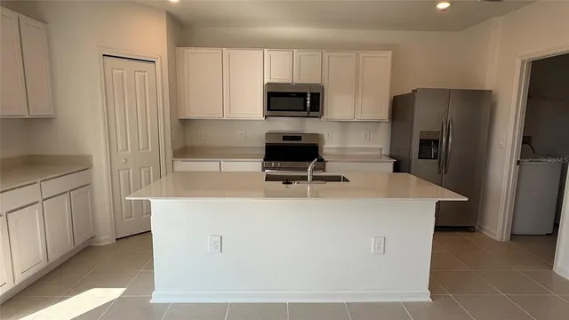 a kitchen with kitchen island a counter top space stainless steel appliances and cabinets